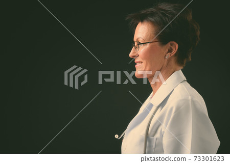 Mature beautiful woman doctor with short hair against black background Mature beautiful woman doctor with short hair against black background 73301623