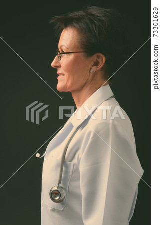 Mature beautiful woman doctor with short hair against black background Mature beautiful woman doctor with short hair against black background 73301629