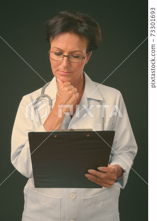 Mature beautiful woman doctor with short hair against black background Mature beautiful woman doctor with short hair against black background 73301693