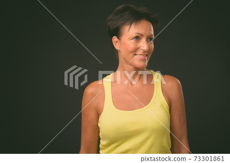 Mature beautiful woman with short hair against black background 73301861