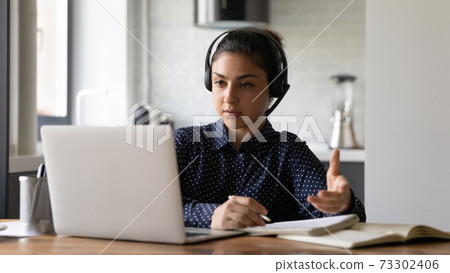 Concentrated young Indian woman have webcam lesson on laptop 73302406