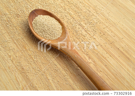 Active granulated yeast, instant dry sourdough, on bamboo cutting board in wooden spoon 73302916