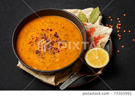 Ezogelin Soup in black bowl on dark slate table top. Turkish cuisine traditional dish Ezogelin Soup in black bowl on dark slate table top. Turkish cuisine traditional dish 73303991