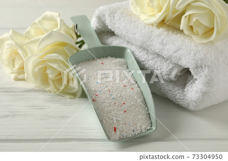 Scoop with powder, roses and towels on white wooden background 73304950