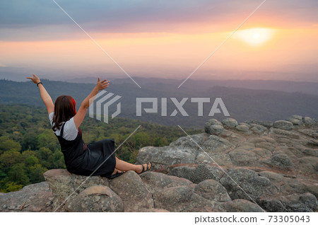 Asian woman raising hands enjoy looking sunset 73305043