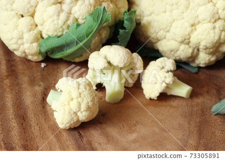 Close up of fresh organic cauliflower on wooden cutting board with copy space. Close up of fresh organic cauliflower on wooden cutting board with copy space. 73305891