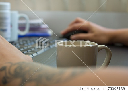 Woman working at home on her computer while drinking an espresso Woman working at home on her computer while drinking an espresso 73307189