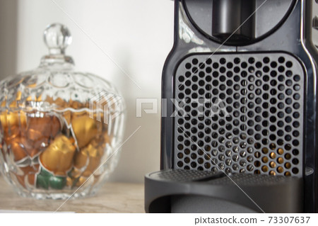 Capsule coffee machine and a glass pot full of capsules 73307637