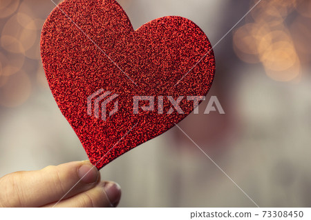 Female hands holding sparkling red heart near body, taking care, Health, Valentine's Day concept romantic design 73308450