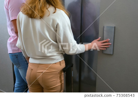 Woman pressing the button of elewator and waiting it, back view. Woman pressing the button of elewator and waiting it, back view. 73308543