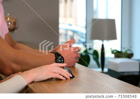 Woman's hands are pressing the bell to call the staff in reception of hotel. Woman's hands are pressing the bell to call the staff in reception of hotel. 73308548