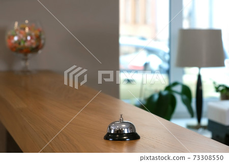 Reception at the hotel with a bell on a wooden table, closeup view. 73308550