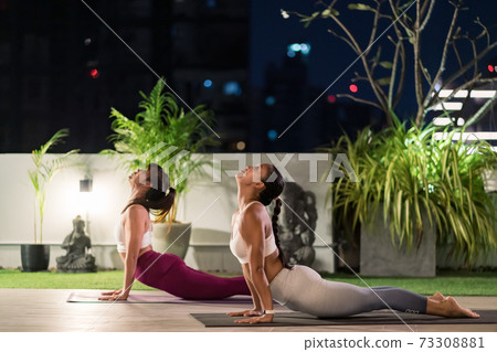 Asian women do yoga in city at night 73308881