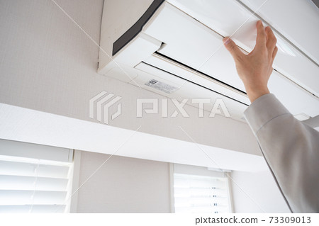 Men's hands maintaining the air conditioner 73309013