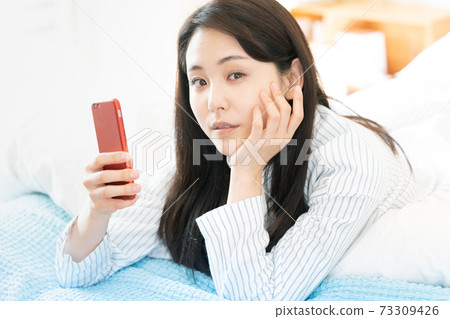 Young woman looking at a smartphone Young woman looking at a smartphone 73309426