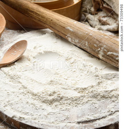 white wheat flour and wooden rolling pin on board, baking ingredients 73309498