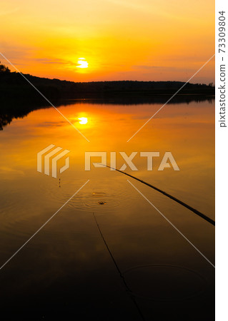 Natural landscape. Sunset over water, reflection of the sun and clouds in the water Natural landscape. Sunset over water, reflection of the sun and clouds in the water 73309804