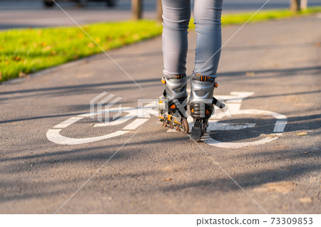 Active leisure. A sportive girl is rollerblading in an autumn park Active leisure. A sportive girl is rollerblading in an autumn park 73309853