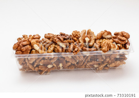 Walnuts in a plastic container on the white background. Walnuts in a plastic container on the white background. 73310191