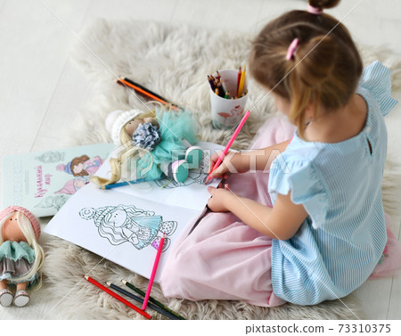 Small girl sitting on soft carpet and coloring 73310375
