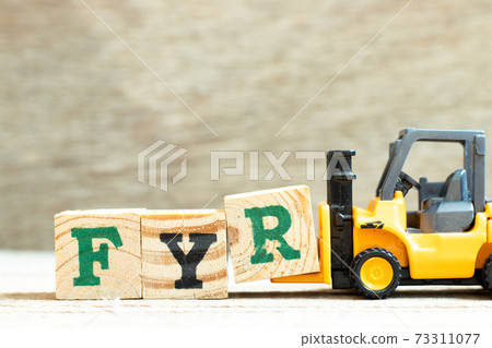 Toy forklift hold letter block R to complete word FYR (abbreviation of for your reference) on wood background 73311077