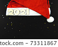 Wooden numbers 2021 on a red Santa hat on a black background. 73311867