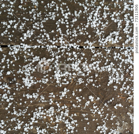 First snow on dirty wooden floor close-up view 73311906