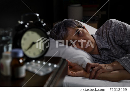 Depressed senior woman lying in bed cannot sleep from insomnia 73312469