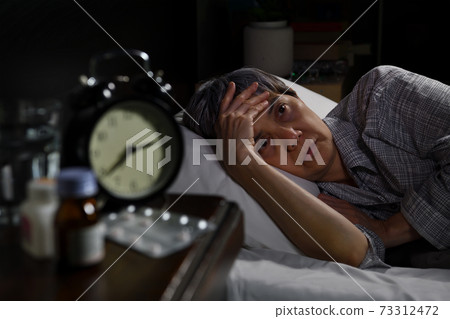 Depressed senior woman lying in bed cannot sleep from insomnia 73312472