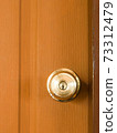 Circle door knob and  brown wood door. 73312479
