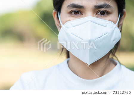 Woman wearing N95 respiratory medical face mask prevent coronavirus Disease (Covid-19) and pm2.5 (particulate matter). healthcare, New normal and air pollution concept, selective focus on Mask Woman wearing N95 respiratory medical face mask prevent coronavirus Disease (Covid-19) and pm2.5 (particulate matter). healthcare, New normal and air pollution concept, selective focus on Mask 73312750