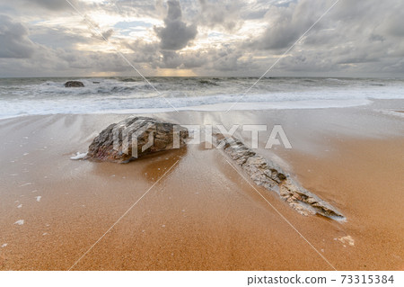 Rocks on a sandy beach in the Atlantic Ocean 73315384