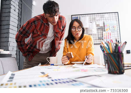 Designer looking at the paper with sample of design 73316300