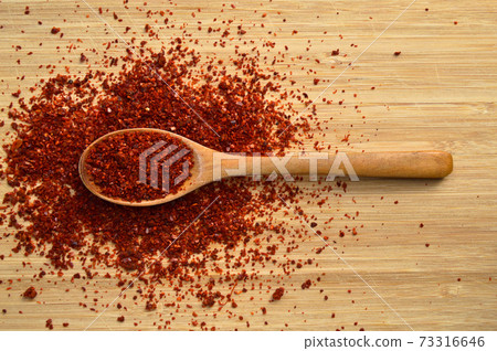 Dried red pepper in wooden spoon on bamboo cutting board 73316646