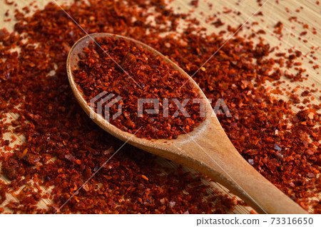 Dried red pepper in wooden spoon on bamboo cutting board 73316650