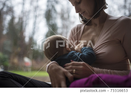 Young mother breastfeeding her tiny baby 73316653