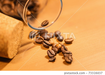 Roasted coffee beans on table with jar Roasted coffee beans on table with jar 73316837