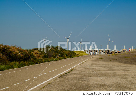Netherlands, August 2019. In Zeeland, wind farms are the setting for the immense dam that governs the flow of sea waters, securing the territory. 73317070