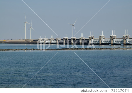 Netherlands, August 2019. In Zeeland, wind farms are the setting for the immense dam that governs the flow of sea waters, securing the territory. 73317074