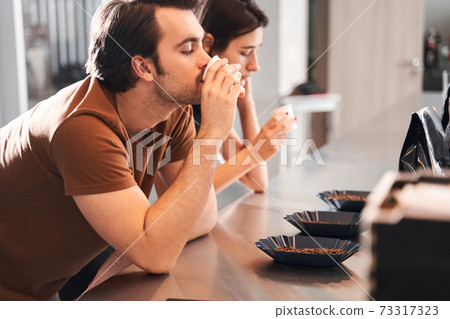Rows of cups and beans with baristas 73317323