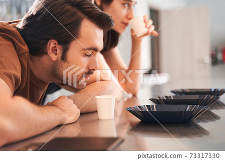 Rows of cups and beans with baristas 73317330