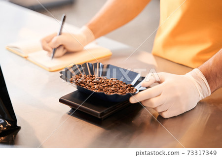 Man weighing coffee beans before the filling bags Man weighing coffee beans before the filling bags 73317349