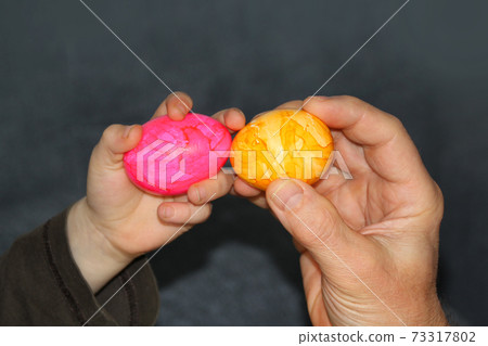 the child holds one pink egg in his hand, the adult has yellow, the concept of Easter fun the child holds one pink egg in his hand, the adult has yellow, the concept of Easter fun 73317802