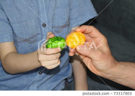 the child holds one green egg in his hand, the adult has yellow, the concept of Easter fun the child holds one green egg in his hand, the adult has yellow, the concept of Easter fun 73317803