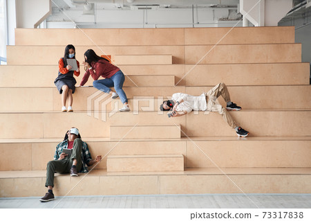 Attractive groupmates spending time together at the stairs Attractive groupmates spending time together at the stairs 73317838
