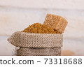 Brown cane sugar in a bag with a cube of shed on top 73318688
