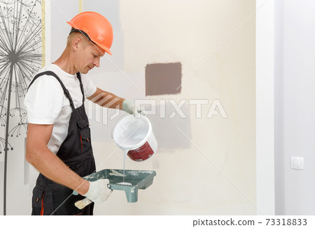The painter is painting a wall in a room with a roller. 73318833