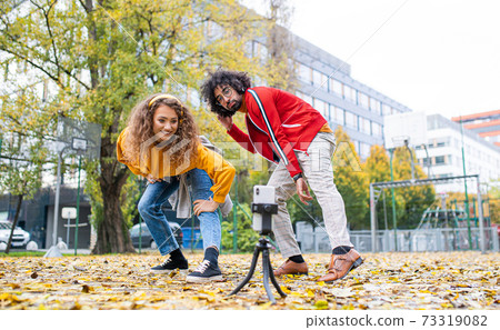Young couple with smartphone making video for social media outdoors in park. Young couple with smartphone making video for social media outdoors in park. 73319082