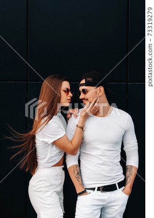A beautiful couple in love in white stylish clothes are walking in the city A beautiful couple in love in white stylish clothes are walking in the city 73319279