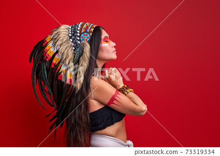 side view on long haired shaman woman with feathers on head 73319334